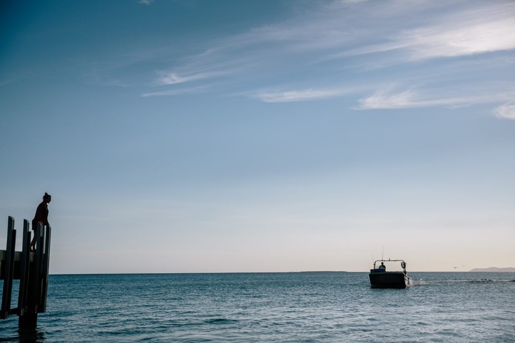 Jo Barett on the pier looking at a fishing boat in the sea