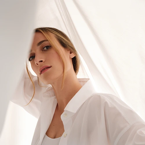 A blonde lady posing between white sheets