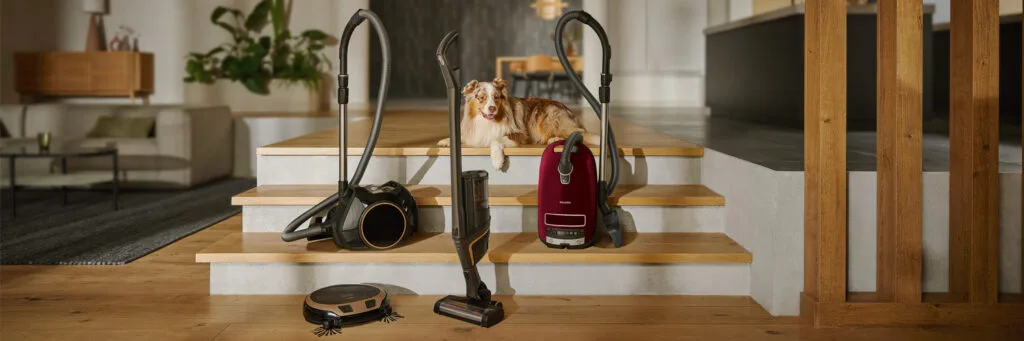 Miele range of vacuum cleaners on display next to a dog