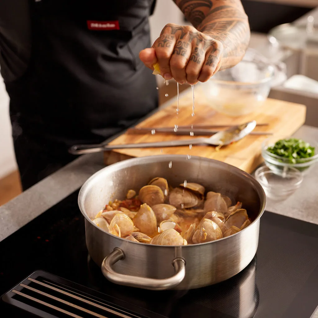 Cloudy bay clams in a stainless steel cookware on a Miele induction cooktop