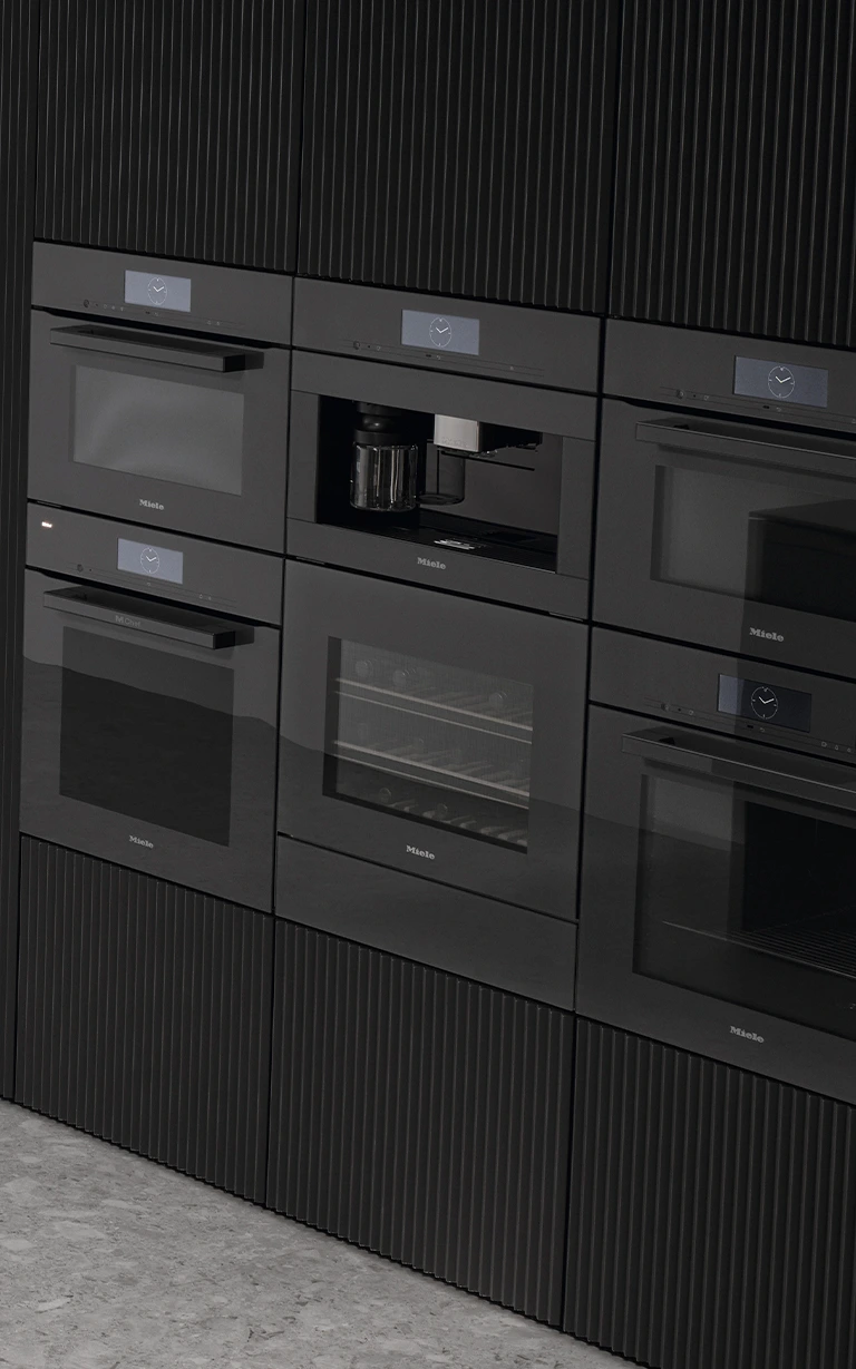 Black Miele coffee machine and ovens built into kitchen cupboards.