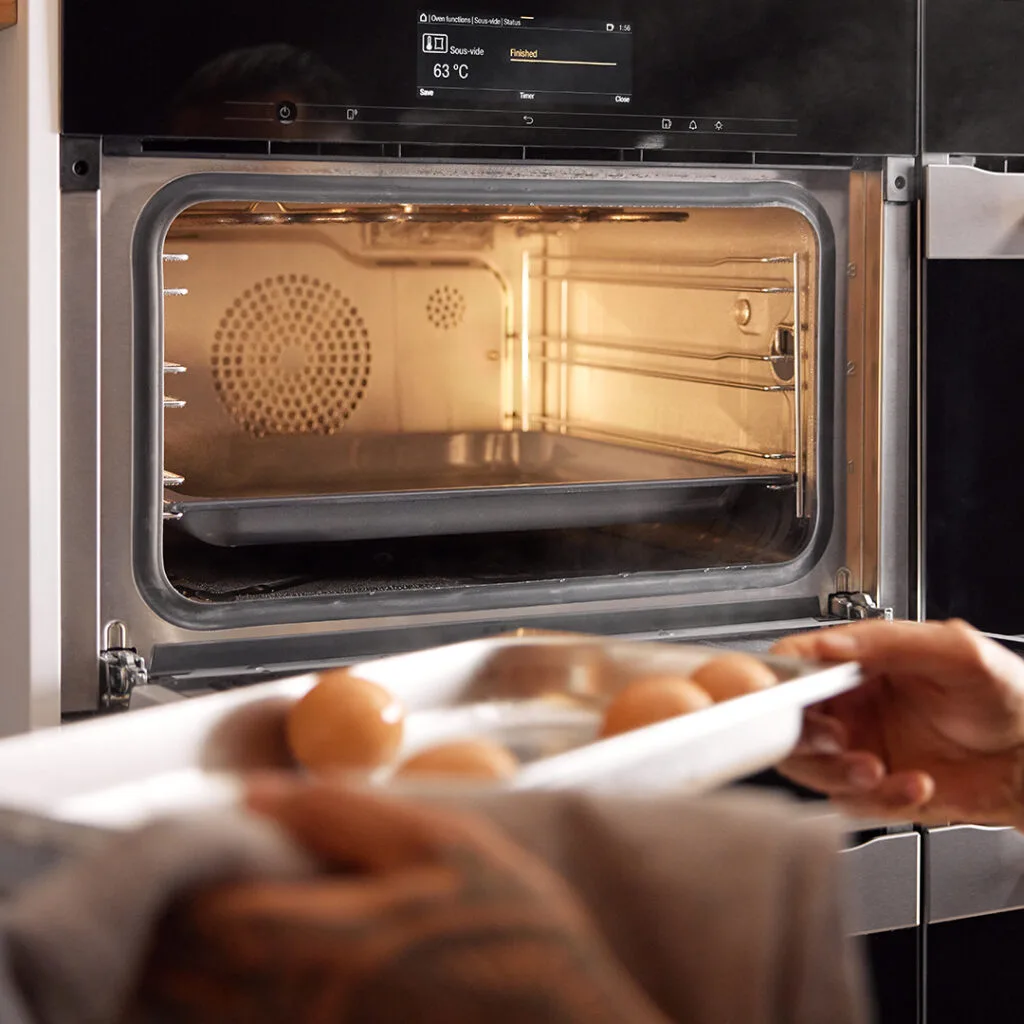 A tray of eggs being put into a Miele steam oven to be cooked.