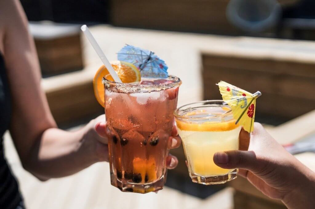 two people clinking their glasses of summer drinks